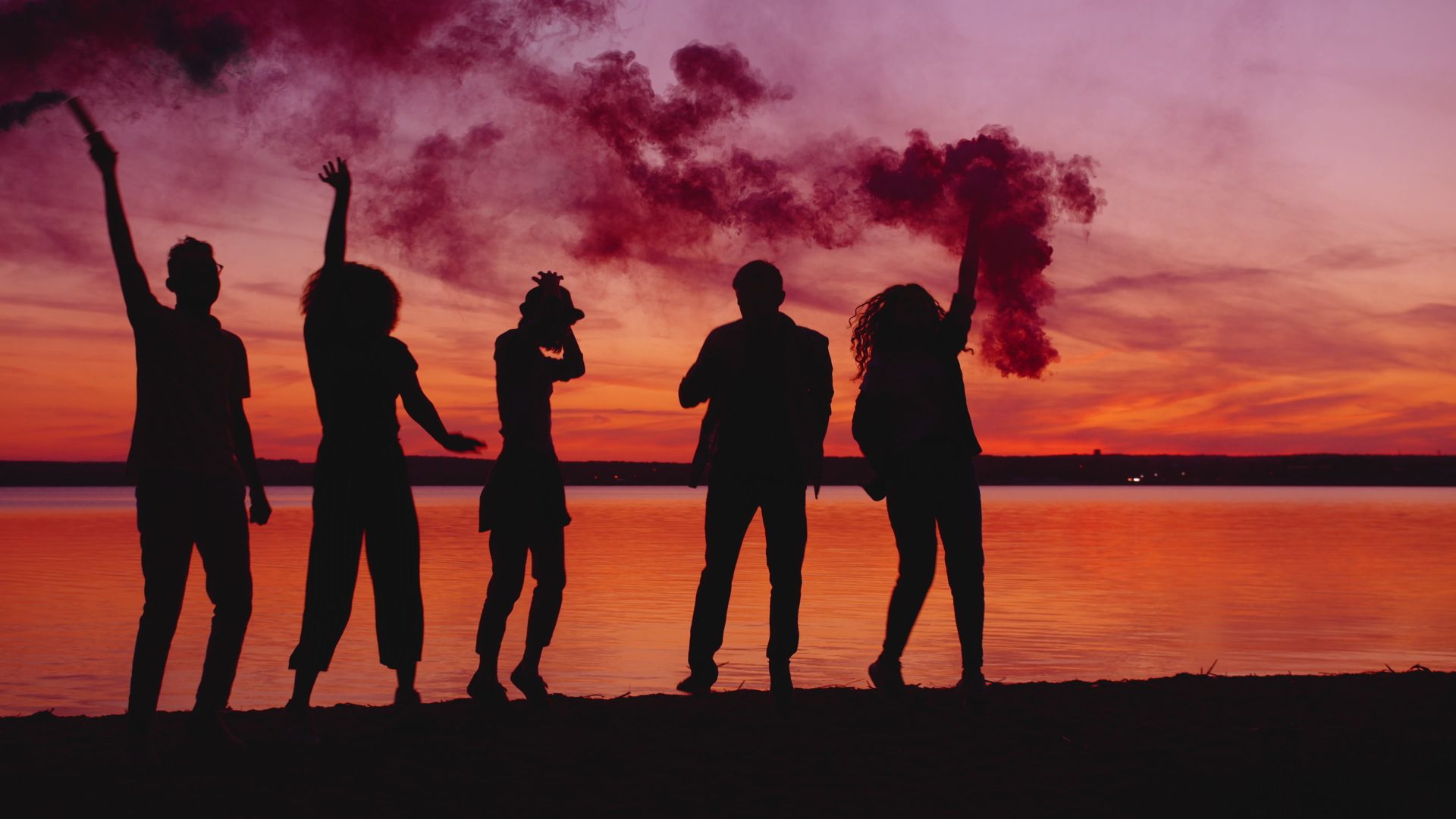 Friends in silhouette celebrating at dusk
